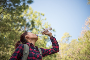 Happy woman tourist with backpack drinking water in nature.