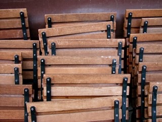 Aufgereihte zusammengeklappte Holzstühle und Klappstühle in Braun vor einem Café in den Gassen...