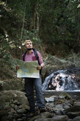 Obraz premium Adventure man observing map on a mountain path to find the the right way.