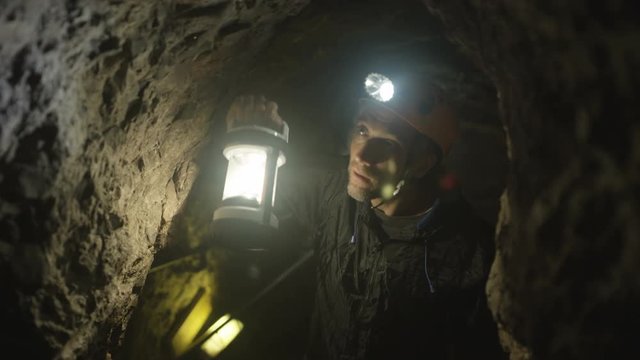  Team of potholers with hard hats and lamps exploring underground cave system