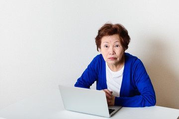 パソコンを使っている高齢のアジア人女性