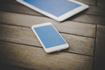 Smartphone and tablet on a wooden table.