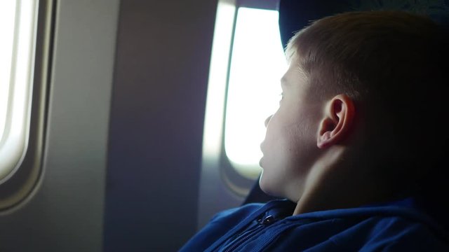 A child looking out the window of an airplane on a sunny day