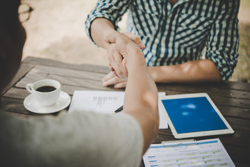 Close-up of two business people shaking hands while sitting at the working place.