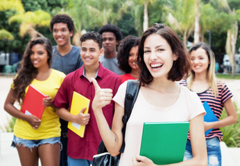 Lachende deutsche Studentin mit anderen Stundenden auf dem Campus