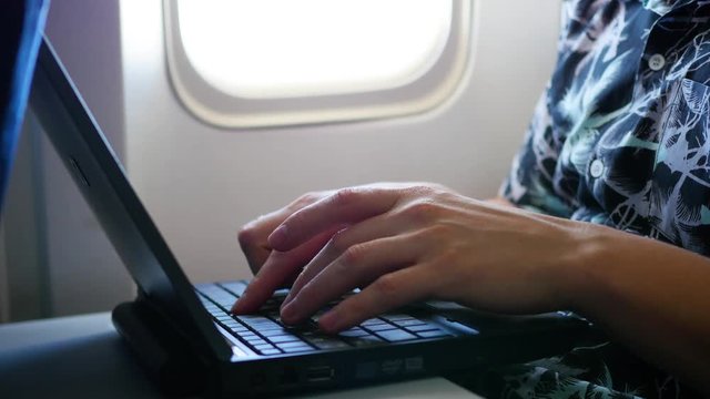 guy working on laptop in the airplane near the window