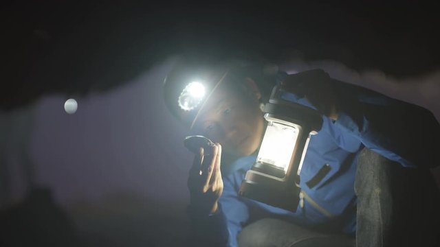  Geologist exploring underground cave, studying rock formation