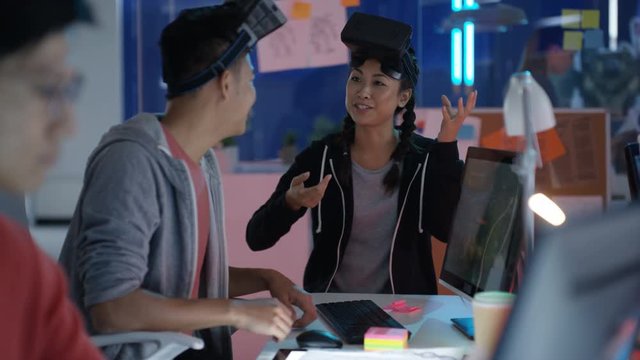  Young computer game designers looking into VR viewers & discussing a project.