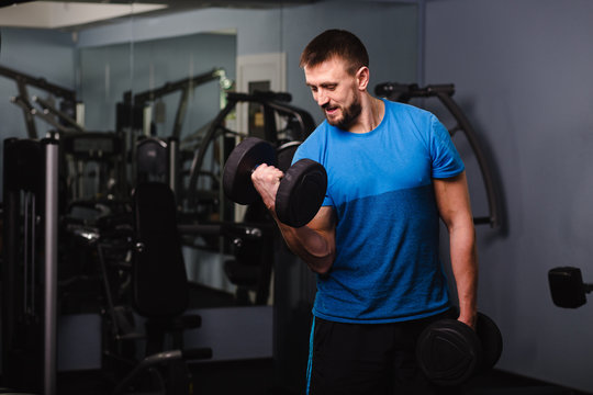 muscular, attractive man training biceps, lifting a dumbbell. Training at the gym for muscular arms.