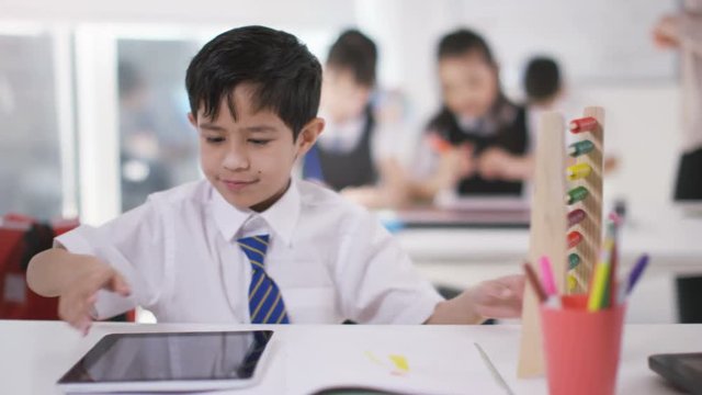  Young school children in class with little boy using abacus & computer tablet