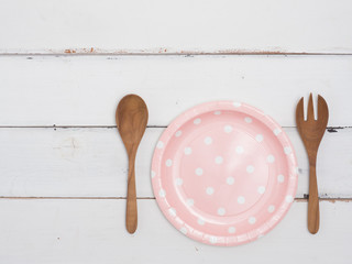 Top view empty color dish, fork and spoon on wooden table.Color dish has pattern  dot.