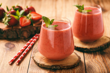Strawberry smoothie in glass on wooden stump.