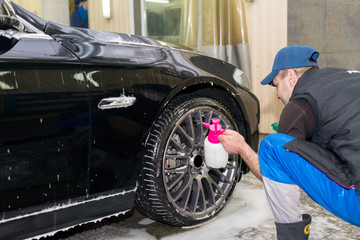 A man washes a black car