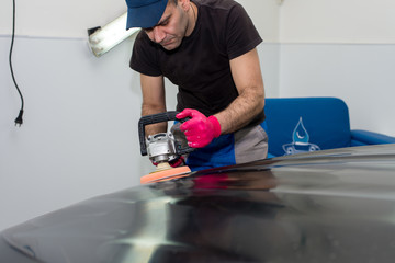 A man polishes a black car