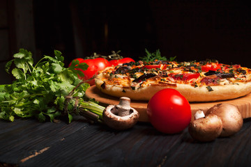 Fresh tasty pizza on black background on rustic wooden table with ingredients. Italian food.
