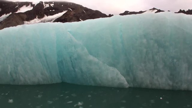 Moving Ice Floes on background of mountain on water of Arctic Ocean in Svalbard. Wildlife in Nordic badlands. Unique footage on background natural landscape and snow of Spitsbergen.