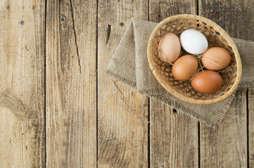 Eggs of different colors on wooden background