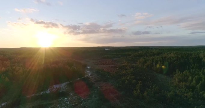 Swamp, Cinema 4k flying against the orange sunset sun, over a icy swamp and fields in the finnish forrest, on a sunny spring evening, in Uusimaa, Finland