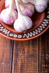 Garlic in brown plate wrapped with twine on wooden background. Rustic.