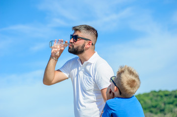 Portrait of father  teasing and not giving water to his thirsty handsome son on the desert tropical...