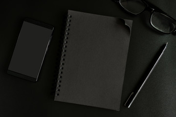 Black notebook and cellphone on desk office