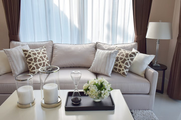 modern living room with sandglass, flower and row of pillows on sofa