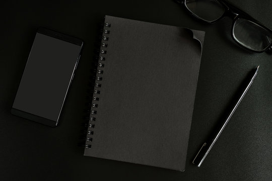 Black notebook and cellphone on desk office