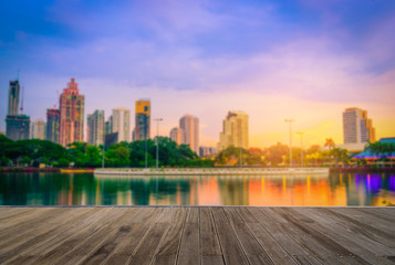 Obraz premium Wooden floor with blurred abstract background of Benchakitti Park at sunset sky in Bangkok, Thailand.