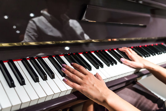 Young woman hands playing on piano (shallow DOF)