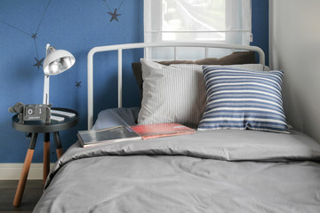 Beige and striped pillow on modern style bed setting and the blue wall bedroom