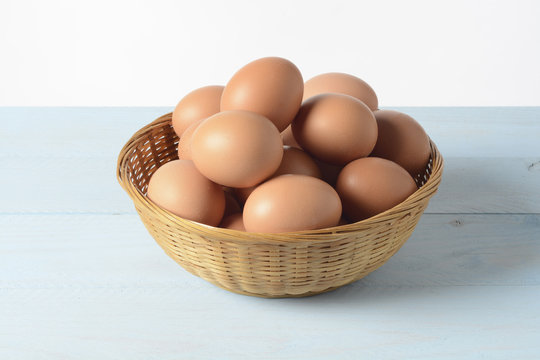 Huevos en un cesto de mimbre sobre fondo de madera