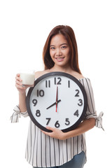 Healthy Asian woman drinking  glass of milk hold clock.