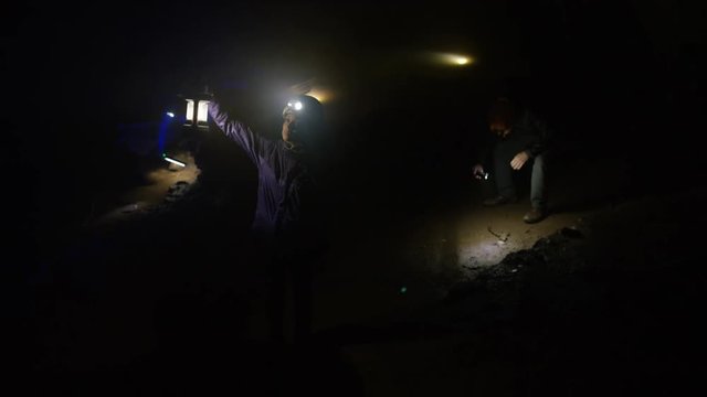  Team of geologists exploring underground cave, looking at rock formation