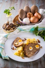 Portion of meatloaf on white plate with potatoes