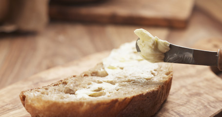 female teen hand spreads butter on slice of rustic bread, 4k photo - obrazy, fototapety, plakaty