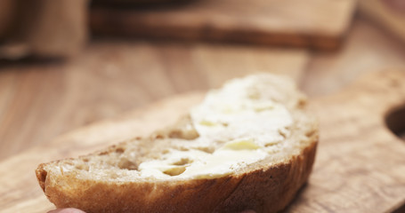 female teen hand spreads butter on slice of rustic bread, 4k photo