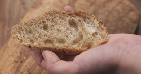 slice of fresh rustic bread in teen hand, 4k photo