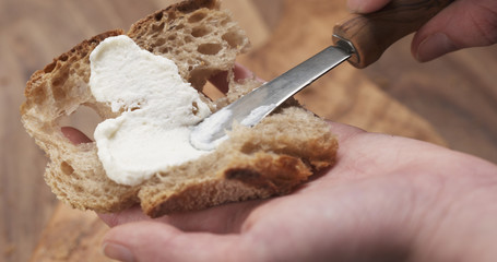 spreading ricotta cheese on fresh rustic bread 4k photo