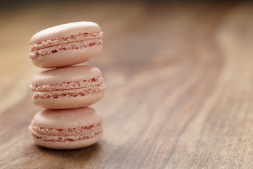 Fototapeta na wymiar closeup shot stack of pastel colored macarons with rose flavour on wood table, copy space