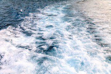 Waves, foam and wake caused by boat in the sea