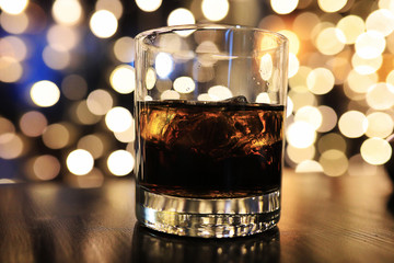 glass of alcohol with ice on blured background with circle bokeh