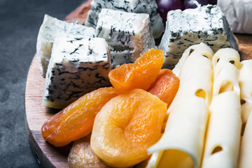 Assorted cheeses with grapes and nuts on a wooden table