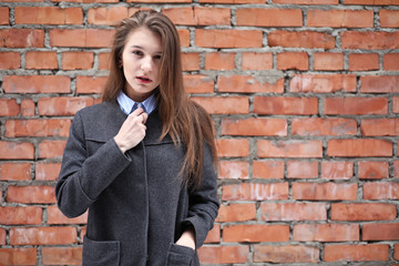 Fototapeta na wymiar Young beautiful girl near red brick wall posing