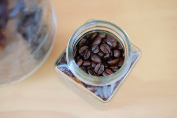 Coffee beans in spoon in glass jar