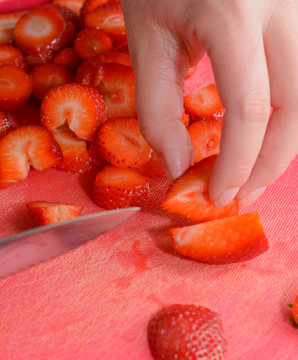 R&uuml;sten von Erdbeeren f&uuml;r Obstsalat auf R&uuml;stbrett