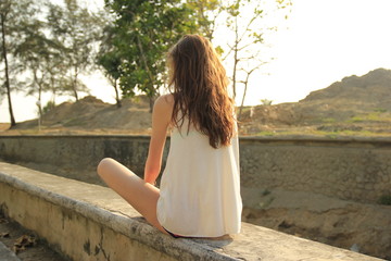 Girl sitting in yoga lotus positions and watch at a sunset