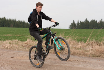 Obraz premium Young man on mountain bike jumps on path