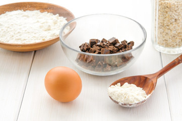 Food ingredients and kitchen utensils for cooking oat cookies on white wooden background