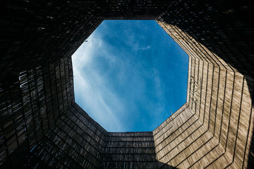 A view of the cloudy sky from inside the power plant cooling towers. Sunlight is on the inner...