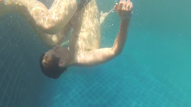 happy guy swims with enjoyment under the water in the pool